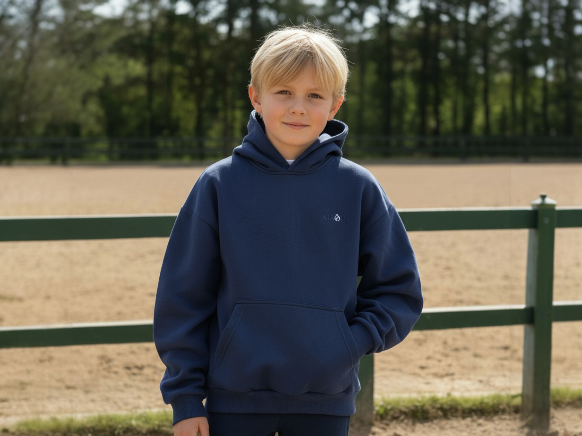 Sweatshirt à capuche bleu marine porté par un garçon et mis en scène dans une ferme