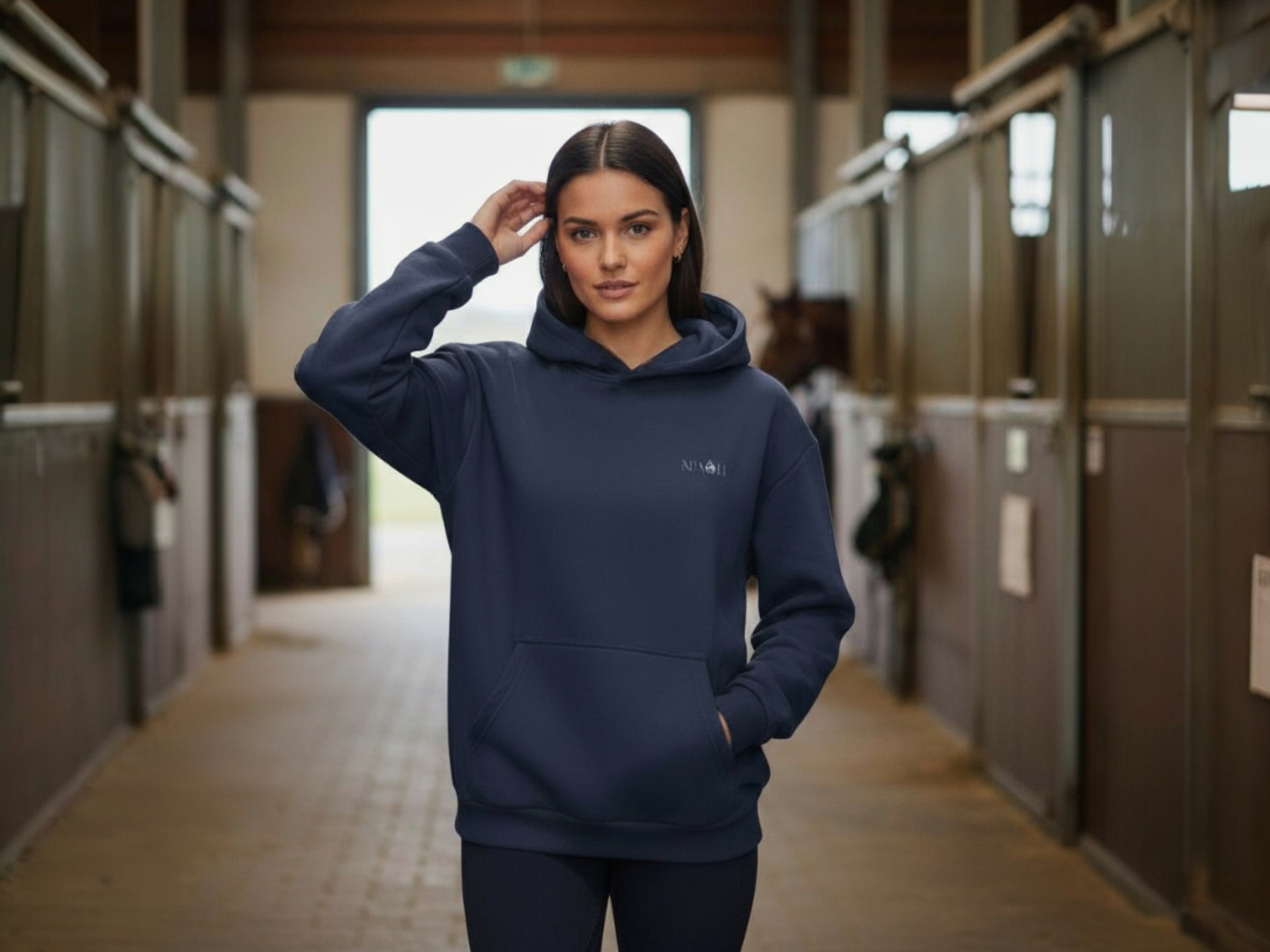 Sweatshirt à capuche bleu marine porté par une femme mis en scène dans une écurie.